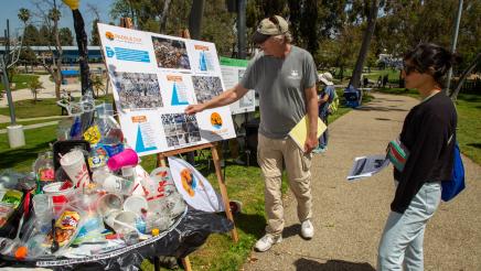 Paddle Out Plastic representative reviewing large display with attendee