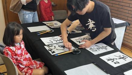 Youth receiving calligraphy lesson from instructor