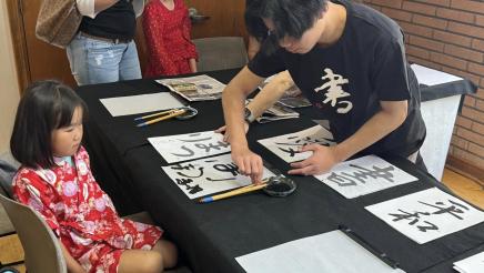 Youth receiving calligraphy lesson from instructor