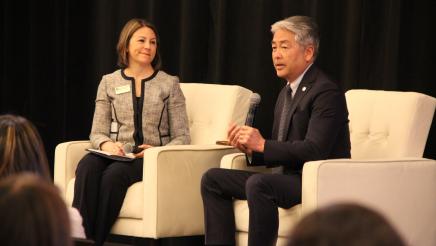 Asm. Muratsuchi speaking and seated with fellow speaker in cushioned chairs onstage