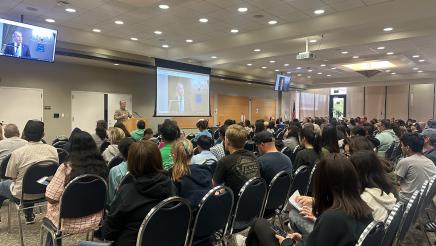 Wide photo of large audeince listening to Asm. Muratsuchi speaking from podium