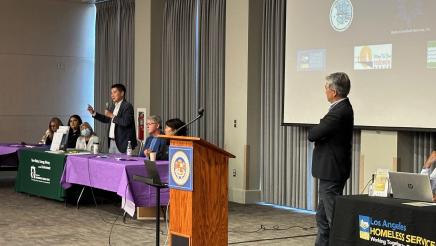 Asm. Muratsuchi listens on as guest speaker stands and speaks into microphone