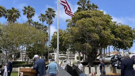 Attendees gathered around memorial with flag pole in middle