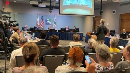 Asm. Muratsuchi at podium in middle of room, speaking to city council members as seated audience members look on