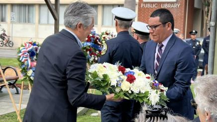 Asm. Muratsuchi and attendee handling a large wreath of flowers