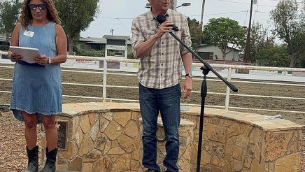 Asm. Muratsuchi onstage, holding microphone and speaking