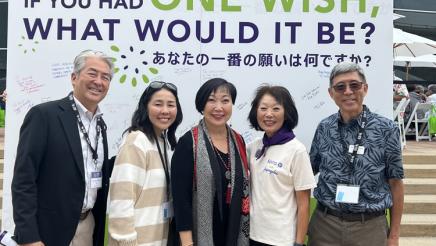 Group photo of Asm. Muratsuchi and attendees in front of large sign