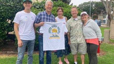 Asm. Muratsuchi with attendees holding a Manhattan Beach Hometown Fair Beer Garden T-Shirt