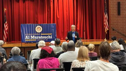 Asm. Muratsuchi in front of the crowd speaking to attendees at the town hall