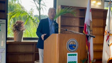 Asm. Muratsuchi standing at podium, speaking