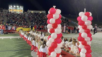 Cheerleaders sitting along sides of red carpet