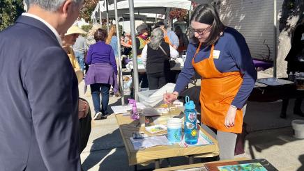 Asm. Muratsuchi standing at art tables, observing live art demonstration