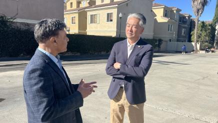 Asm. Muratsuchi speaking with attendee with condos in background