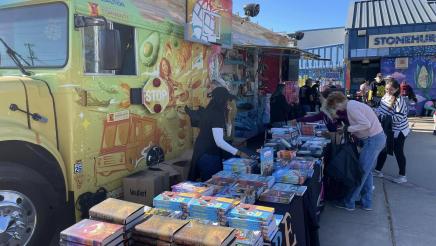 Stacks of books on tables, with staffers helping constituents