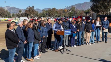 Speaker Rivas at podium, speaking, as multiple assemblymembers stand in support