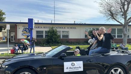Asm. Muratsuchi and family seated high in back of parade car, posing for photo