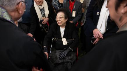 US concentration camp survivor in wheelchair being welcomed by many persons