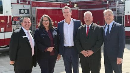 Group photo of Asm. Muratsuchi, Gov. Newsom and others, with fire engines in background