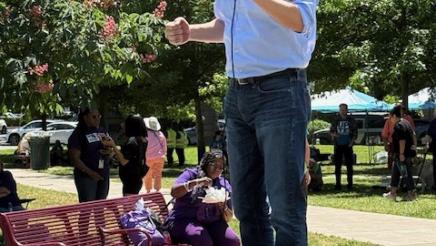 Asm. Muratsuchi onstage in park, speaking into microphone