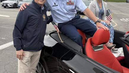 Asm. Muratsuchi standing next to parade car, posing with service member seated in car