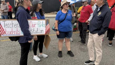 Asm. Muratsuchi speaking with attendees holding signs