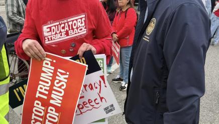 Asm. Muratsuchi speaking with attendee holding multiple signs