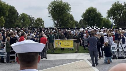 Vietnam veterans carrying banner, with large audience on either side