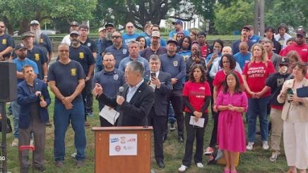Asm. Muratsuchi at podium, speaking, with many CSU employees standing in support