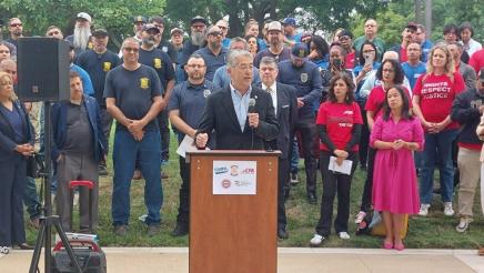 Asm. Muratsuchi at podium, speaking, with many CSU employees standing in support