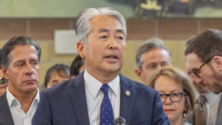 Asm. Muratsuchi at podium, speaking, as others listen on