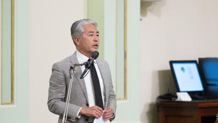 Asm. Muratsuchi standing at microphone, speaking